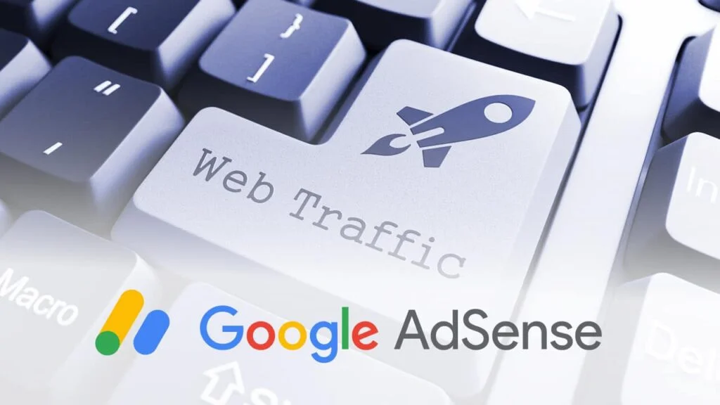 A close-up of a computer keyboard with a key labeled 'Web Traffic' prominently featured and adorned with a rocket ship icon, suggesting a focus on increasing online visitors. The Google AdSense logo is also present, implying that web traffic can be monetized through Google's advertising platform