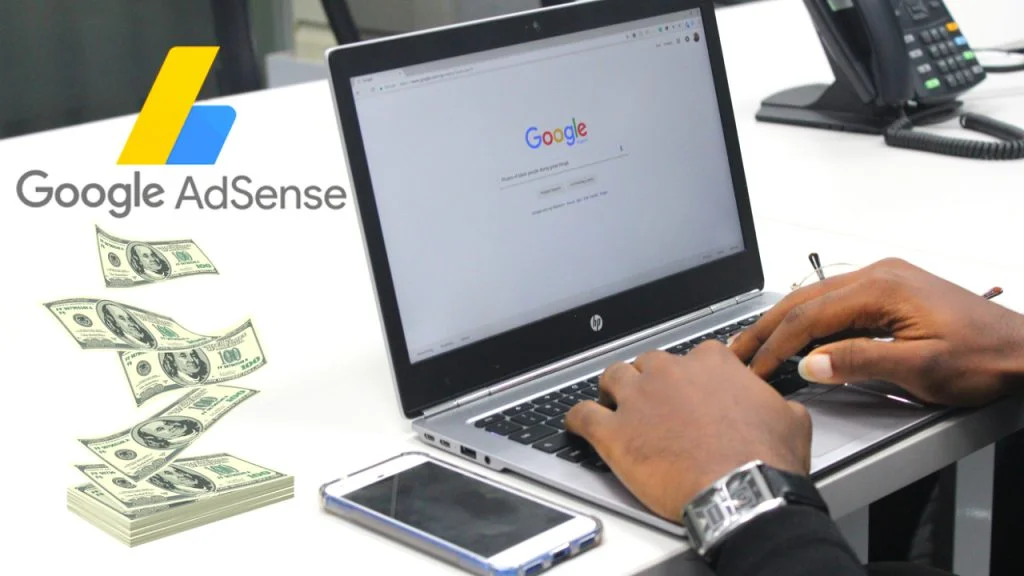 A person's hands are seen typing on a laptop keyboard, which displays the Google homepage on the screen. To the left, a series of hundred dollar bills are fanned out, implying money being made. In the foreground, a smartphone lies next to the laptop. The Google AdSense logo is superimposed in the upper left corner, suggesting the topic is making money online using Google's advertising platform
