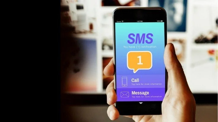 A person’s hand holding a smartphone displaying a notification message with options to call or message for more information, set against a blurred indoor background, symbolizing the potential of push notifications to enhance profits.