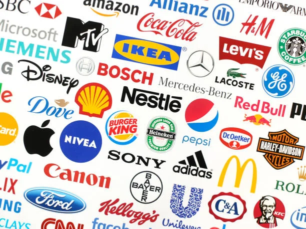 A collage of various famous corporate logos representing a wide range of industries. Among the recognizable brands are tech giants like Apple and Microsoft, automotive companies such as Mercedes-Benz and Ford, consumer goods from Nestle and Coca-Cola, and retailers like Amazon and IKEA. Each logo is distinct in its design, showcasing the diversity of branding strategies in the fields of advertising and marketing. This visual assembly highlights the importance of logos in brand identity and the differences in marketing approaches across sectors.