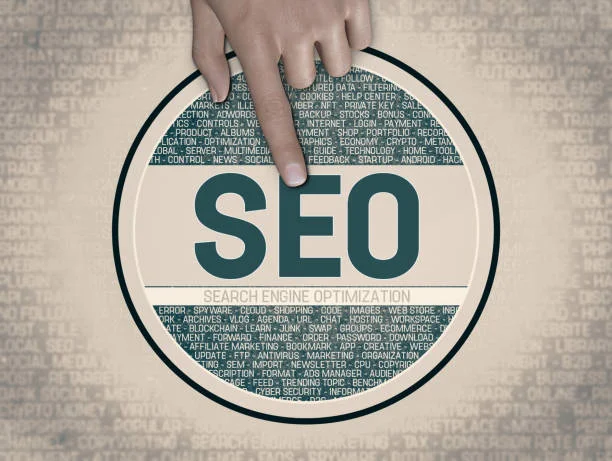 The central focus of the image is a large, round magnifying glass graphic with the acronym 'SEO' in bold teal letters, which stands for Search Engine Optimization. A finger is pressing down on the glass, indicating an action of selecting or focusing on SEO. The background within the magnifying glass contains numerous related terms in smaller print, such as 'analytics,' 'backlink,' 'algorithm,' 'content,' and 'marketing.' These words are arrayed in a scattered fashion, representing the broad range of factors involved in SEO. This visual metaphor highlights the importance of understanding and implementing SEO as part of the content creation and compliance process for effective use of AdSense, as implied by the message 'Mastering AdSense: Essential Guidelines for Content Creation and Compliance