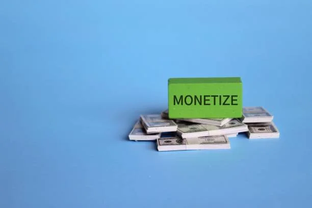 Wooden cube with text MONETIZE and banknotes on blue background. Wooden cube with text MONETIZE and banknotes on blue background. Business and financial concept. ad monetization stock pictures, royalty-free photos & images